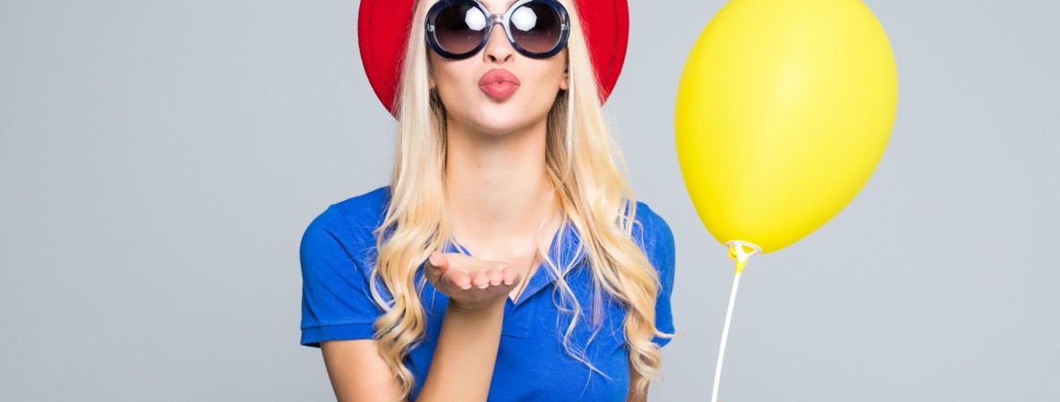 Pretty-young-woman-in-sunglasses-with-air-balloon-sends-an-air-kiss-over-gray-background-845194082_2