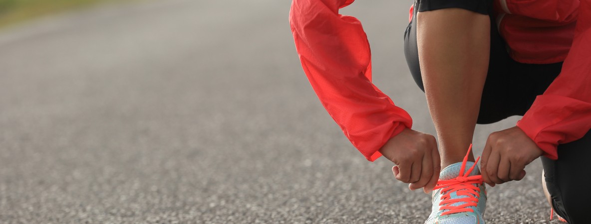 young-woman-runner-tying-shoelace-on-country-road-576927574_5760x3840.jpeg