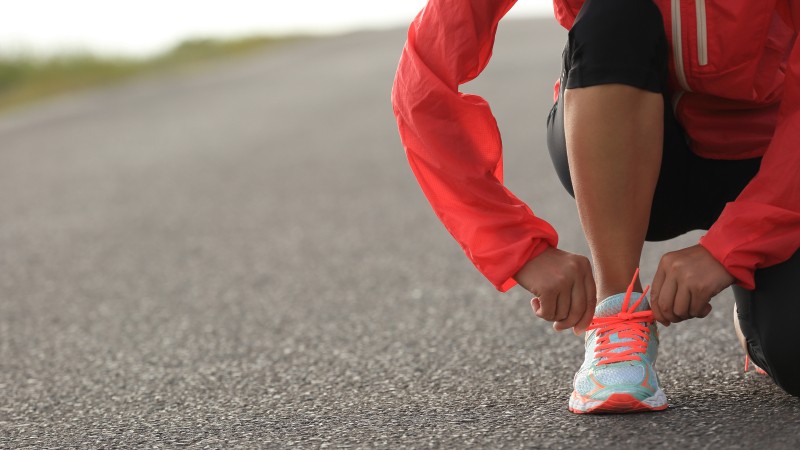 young-woman-runner-tying-shoelace-on-country-road-576927574_5760x3840.jpeg