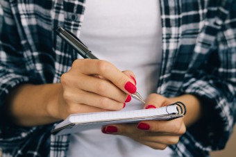 Woman-in-plaid-shirt-and-a-red-manicure-pen-writing-508541368_4898x3265.jpeg
