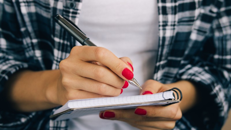 Woman-in-plaid-shirt-and-a-red-manicure-pen-writing-508541368_4898x3265.jpeg
